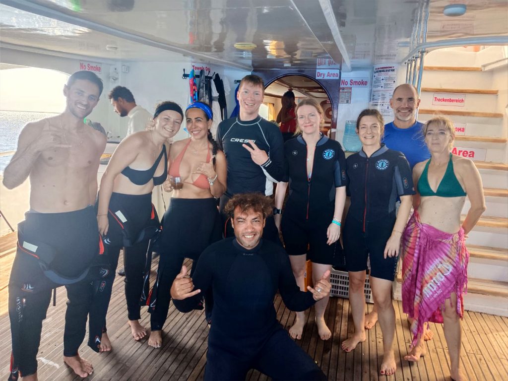 A large group of divers gearing up on the spacious deck of a Hurghada dive boat